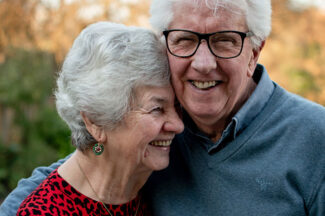 Elderly couple embracing and smiling outside - How does the asbestos claims process actually work?